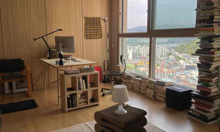 ナチュラルな木目調と大きな窓が特徴のホームオフィス、書籍と照明のある落ち着いた作業空間