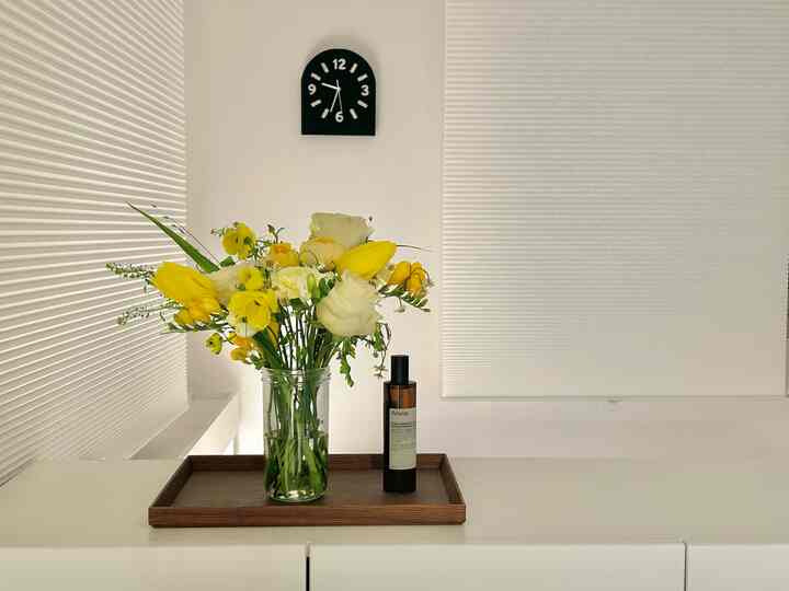 白を基調とした空間、中央に木製トレイに黄色い花束とディフューザーが配置されたシンプルなインテリア