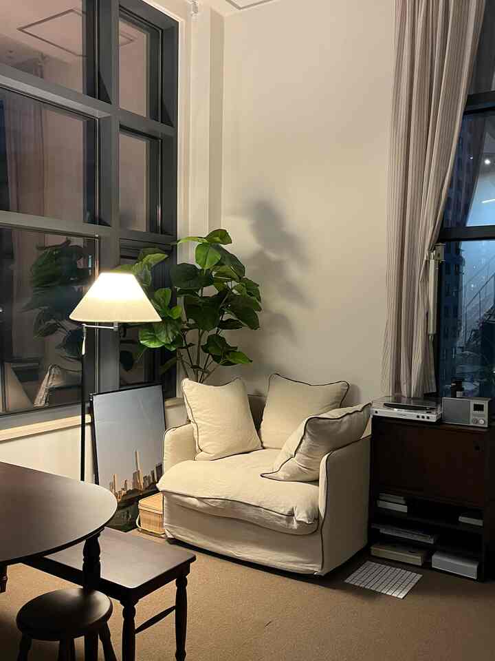 クリーム色のソファとブラウンの家具が調和するナチュラルなリビング、フロアランプと緑の植物が彩る落ち着いた雰囲気のあるインテリア