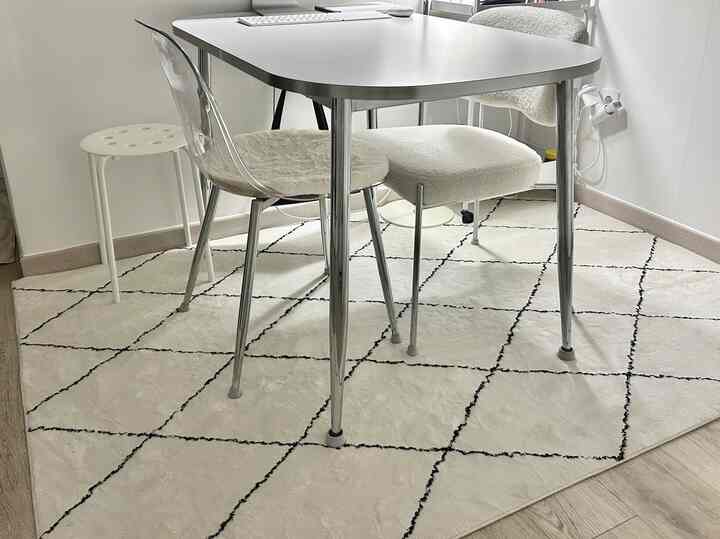 ホワイトとシルバートーンのリビング、白い格子柄カーペットと多様なスツールが配置された、清潔感のあるモダンなインテリア