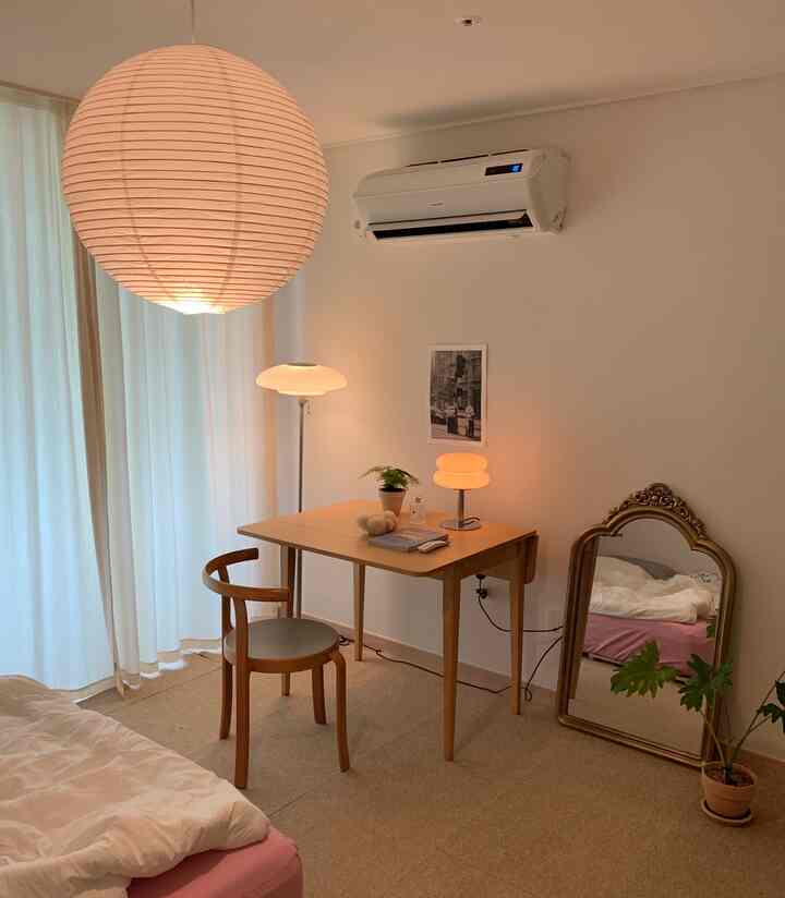 白とライトブラウンのトーンの寝室、木製のテーブルと椅子、フレンチスタイルの鏡、暖かい照明が調和した雰囲気のあるインテリア