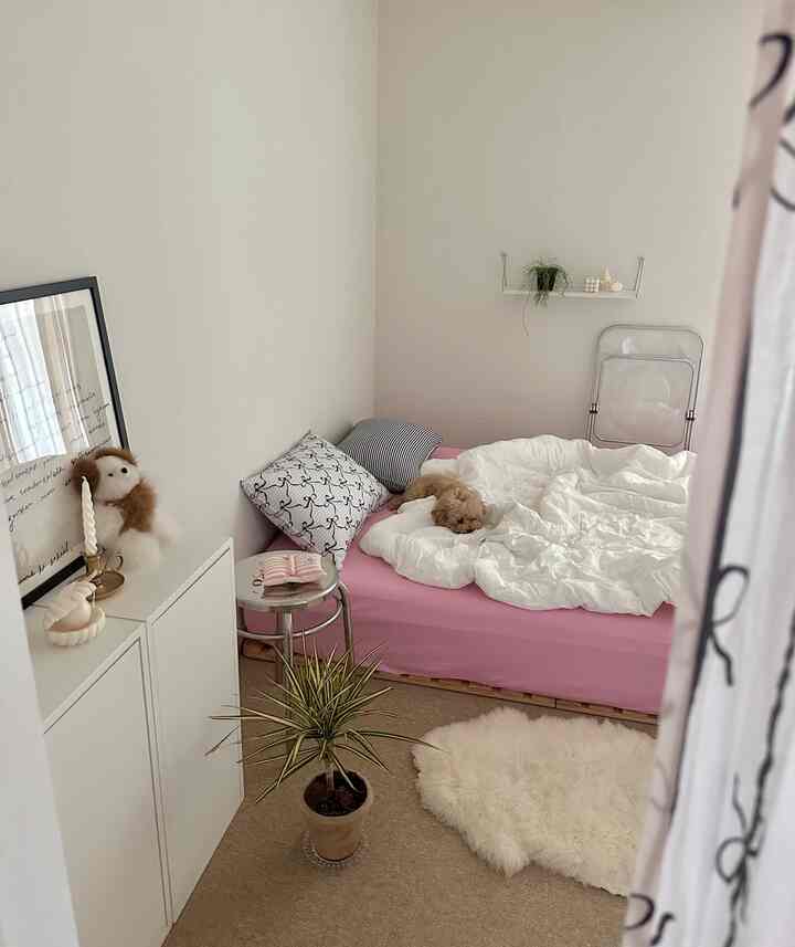 ナチュラルカラーの寝室、ピンクのベッドに白い布団と犬が休む落ち着いた空間