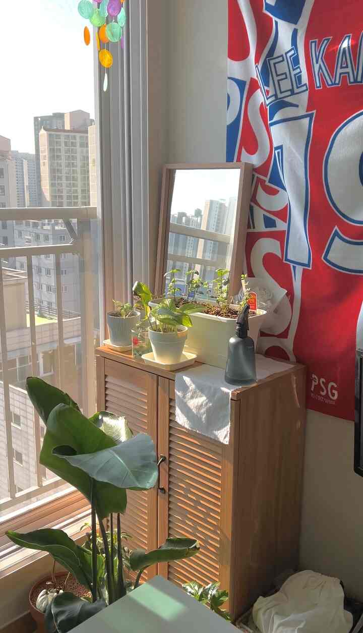 自然光が差し込む白い壁と木目調の収納キャビネットが配置されたバルコニーの見えるナチュラルなリビングルーム