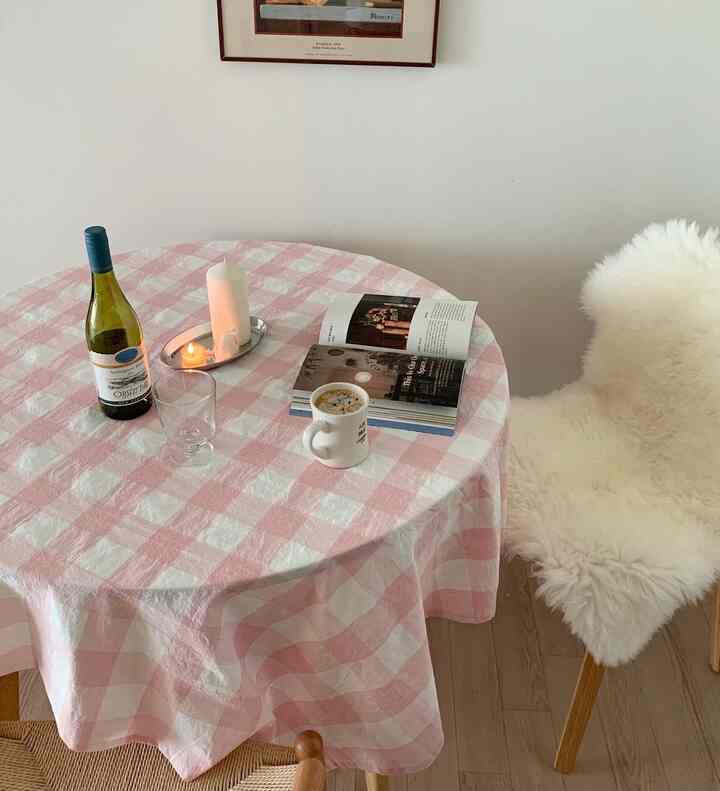 白とベージュの色調のダイニングルーム、ピンクのチェック柄テーブルクロスと白いふわふわクッションが配置された雰囲気のあるおうちカフェ空間