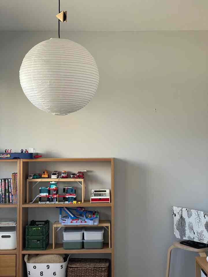 白とナチュラルカラーの子供部屋、整理されたおもちゃ収納棚が配置された落ち着いた雰囲気のインテリア