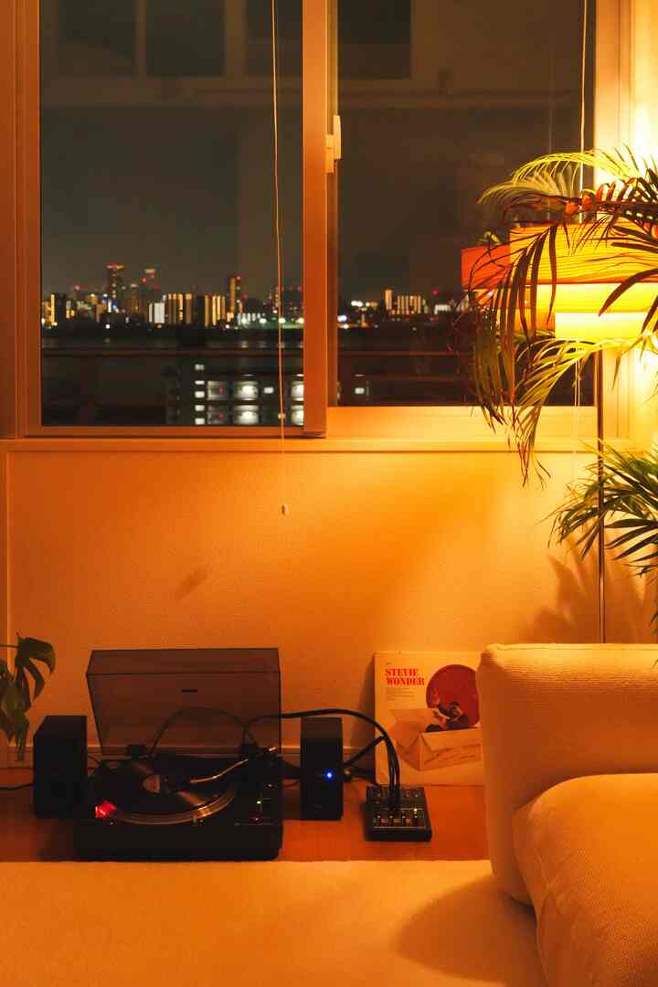 暖かみのあるウッドトーンとナチュラルカラーのリビング、ターンテーブルとフロアランプが配置された雰囲気のあるインテリア