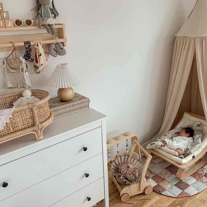 白とナチュラルカラーの子供部屋、キャノピーとベビーベッドが配置された雰囲気のある空間