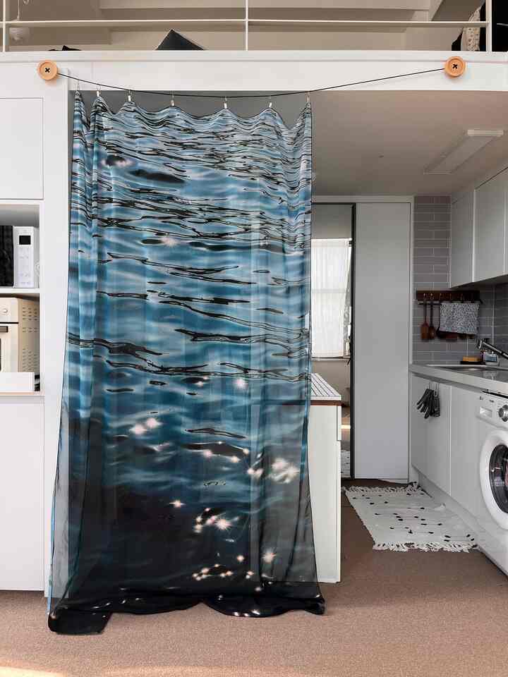 白と茶色のトーンのキッチンスペース、中央に配置されたブルーのファブリックカーテンがある雰囲気のあるインテリア