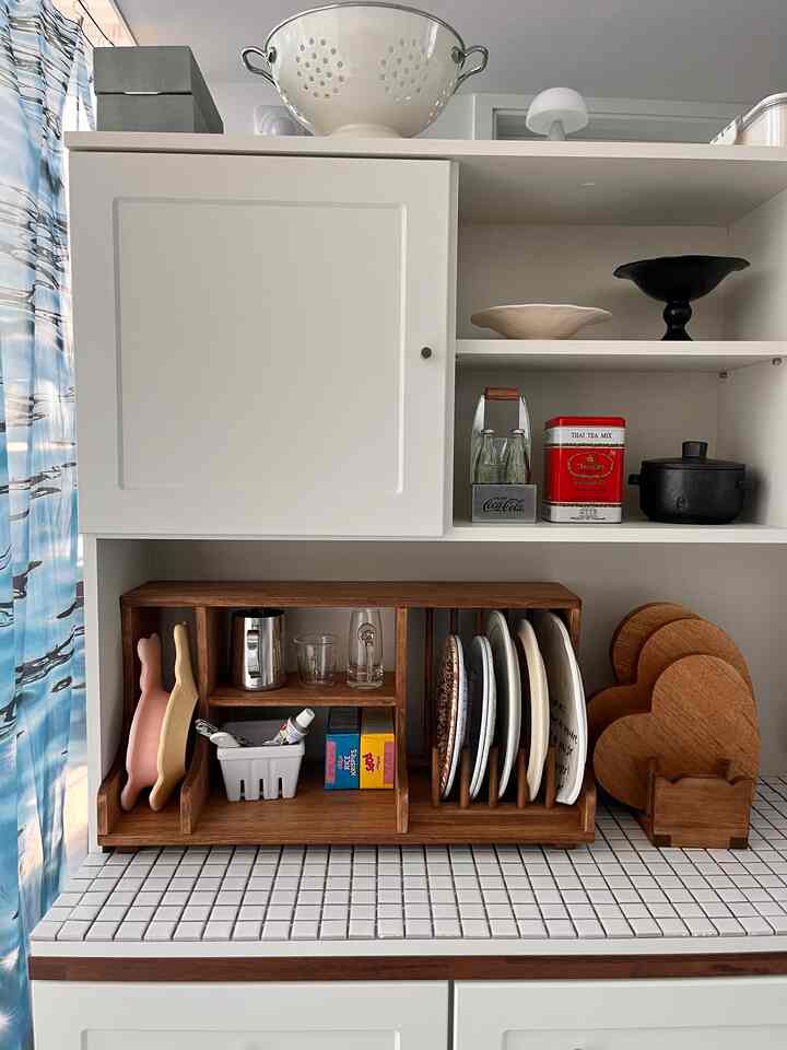 ホワイトと木目調が調和するワンルームのキッチンスペース、オープンシェルフと皿の整頓が印象的なすっきりとしたインテリア