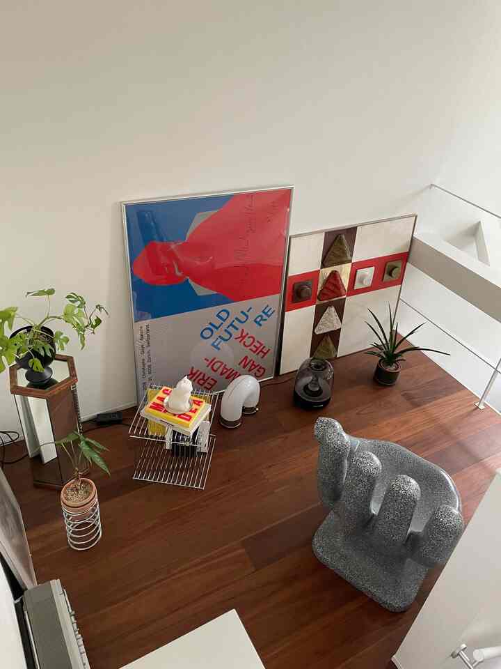 ナチュラルな木目調のフロアにアールデコ風のアートと植物が配置されたモダンなリビングスペース