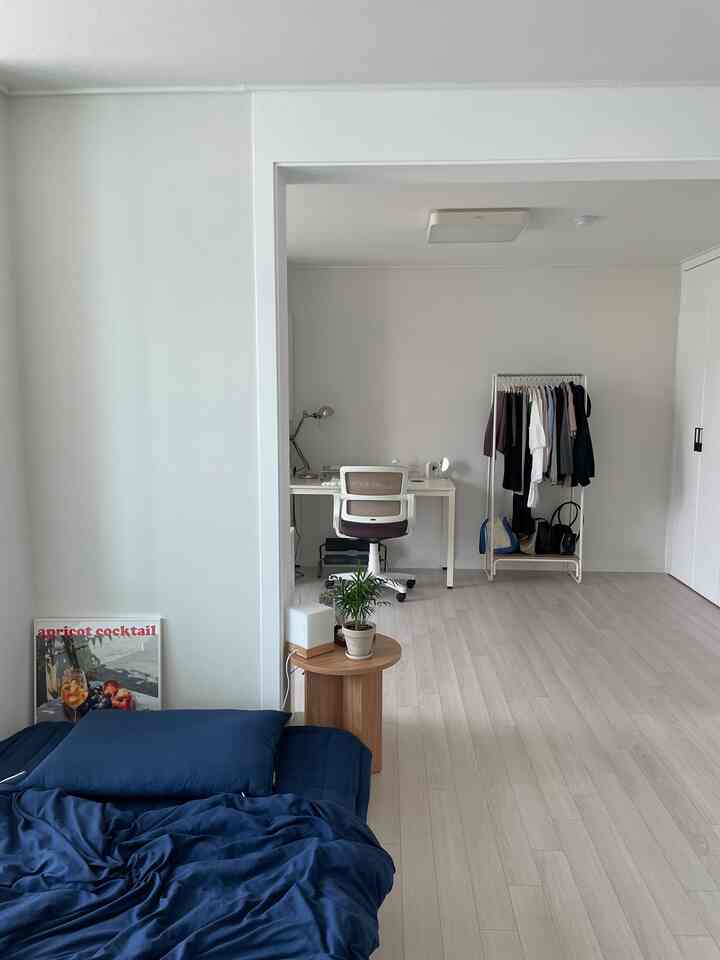 ナチュラルカラーの寝室と奥にホームオフィスが配置された清潔感のある快適な空間