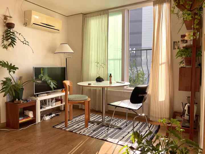 暖かみのある木目調とナチュラルなベージュの色合いが調和したリビング、丸いダイニングテーブルと椅子が配置された心地よい空間