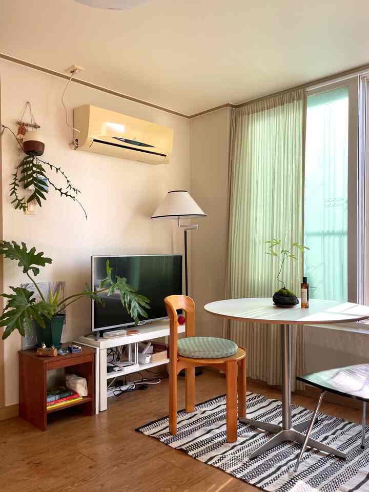 ベージュと木目調のリビング、丸いダイニングテーブルとヴィンテージ家具が配置された温かみのある空間