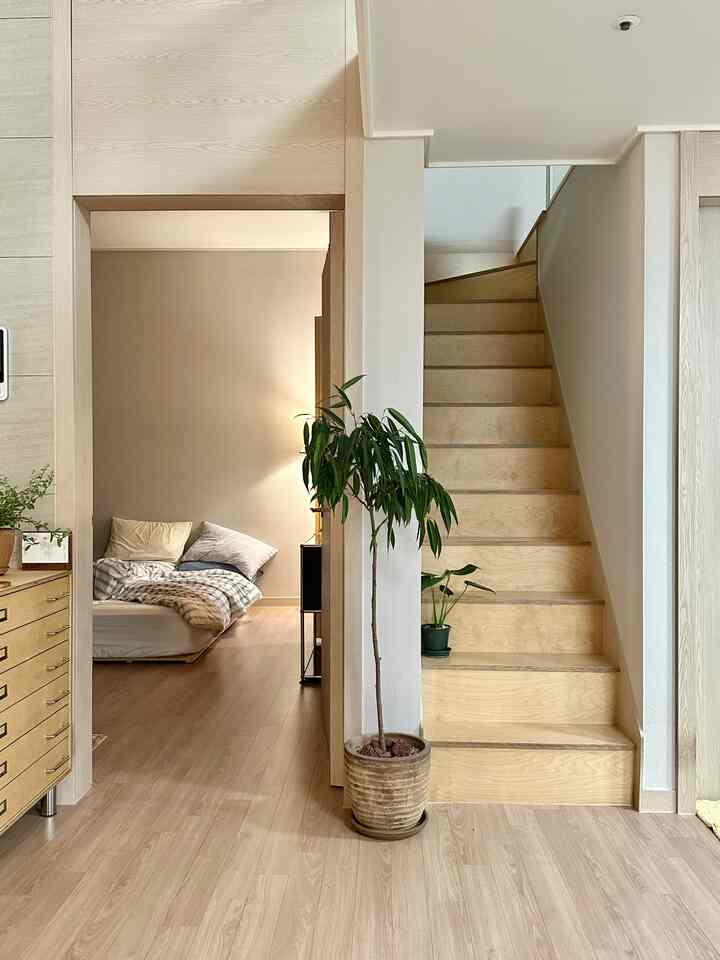 ウッドトーンのナチュラルな複層階段横の寝室空間、シンプルで居心地の良いインテリアが特徴的な空間