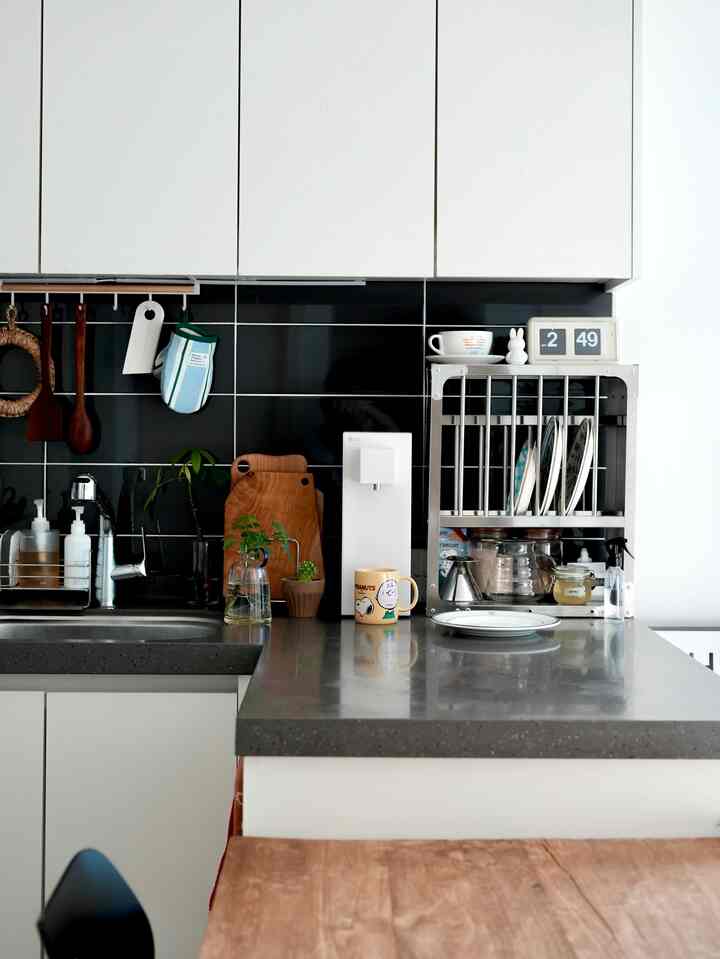 白と黒のトーンのキッチン、シンクと収納ラック、調理器具が整然と配置されたモダンな空間