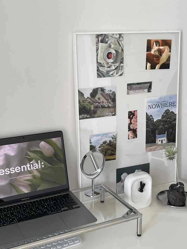 白を基調としたホームオフィス、机の上に額縁、時計、ノートパソコンが配置されたミニマルで清潔感のあるインテリア