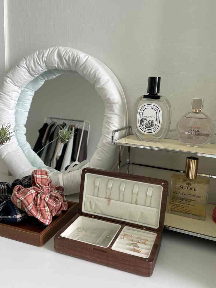 白い壁と木製アクセサリー収納箱、トレイ、丸いパッドミラーが配置されたすっきりとした玄関のインテリア