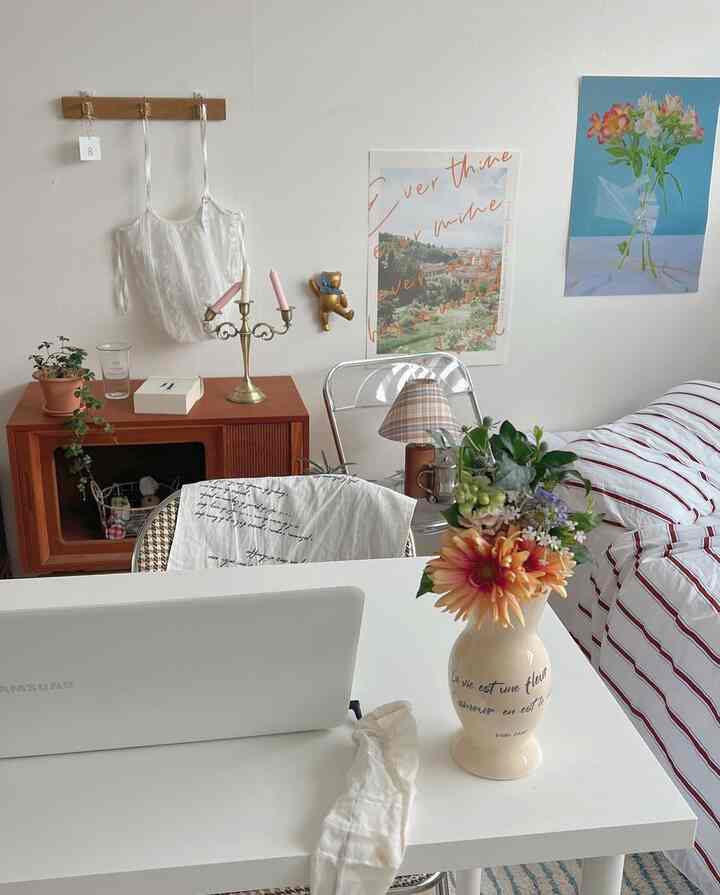 白い壁と木目調の家具が調和する寝室、整ったデスクと居心地の良いベッドが配置された温かみのあるインテリア