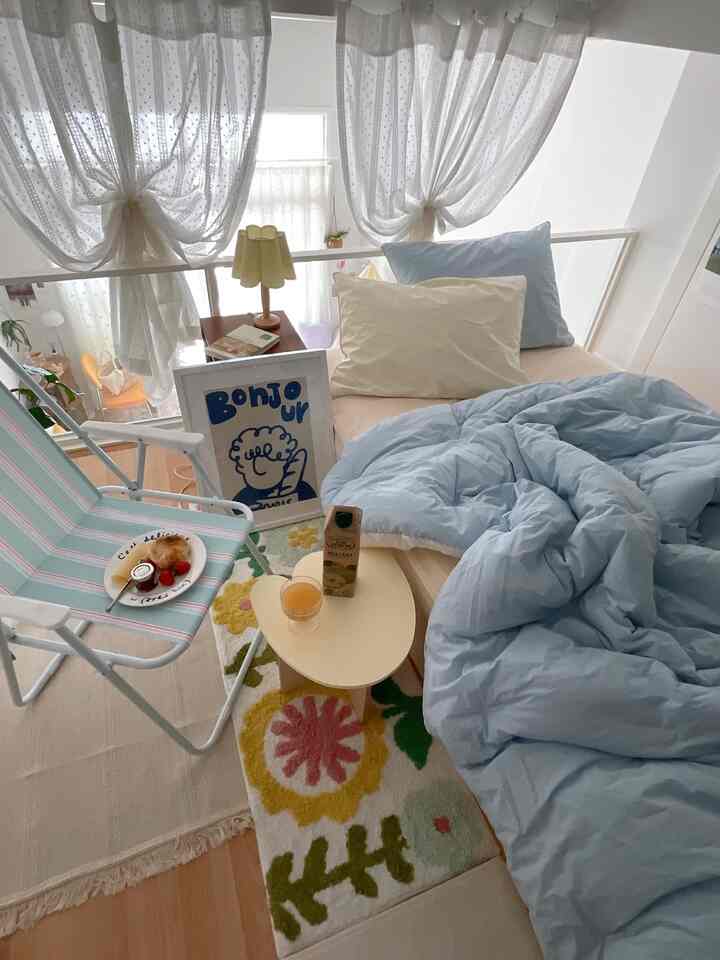 白と青の色調のロフト寝室、白いカーテンとかわいらしい小物が配置された印象的な空間