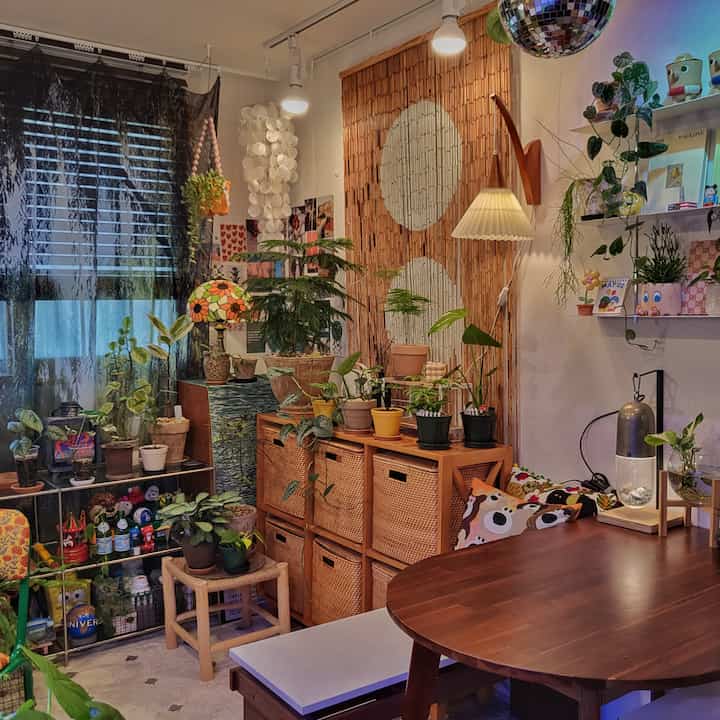 ブラウンとナチュラルな色調のリビング、たくさんの植物とラタンの収納が配置された雰囲気のある空間