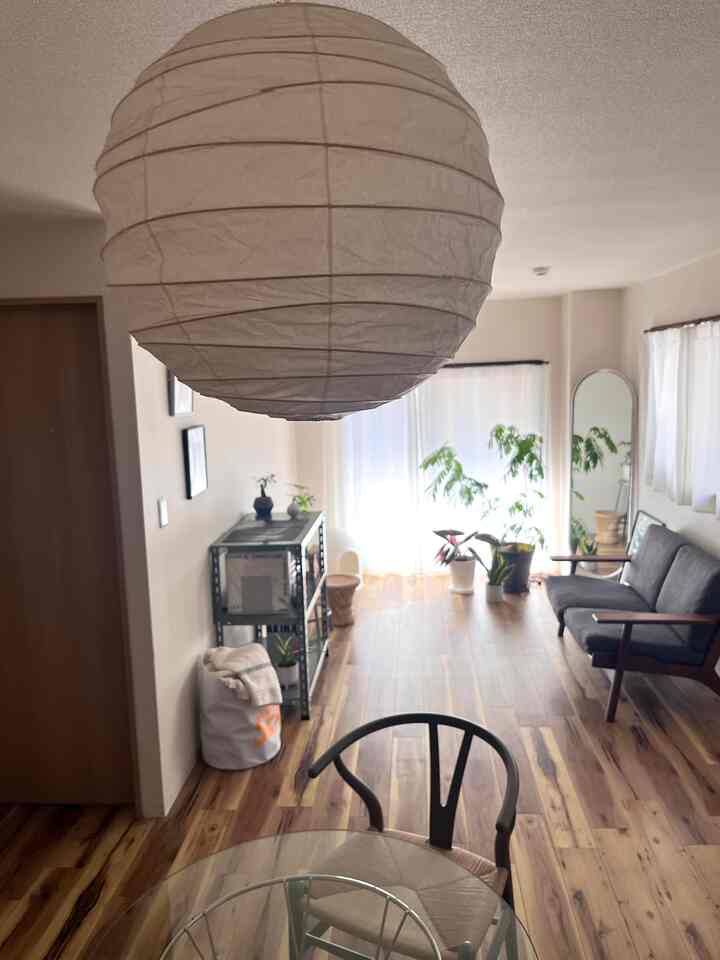 白と木目調の調和が美しいダイニング、中央にペンダントライトとガラスのダイニングテーブルが配置された印象的な空間