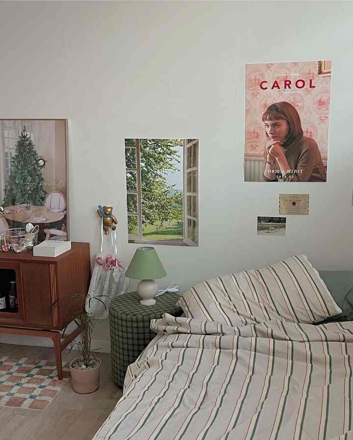 ナチュラルな色調の寝室、ストライプ柄の寝具とチェック柄のオットマン、ヴィンテージ風の小物が配された雰囲気のある空間