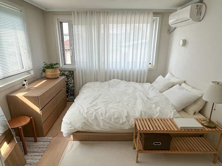 ウッドトーンと白が調和したコンパクトな寝室、シンプルで自然な雰囲気のインテリア