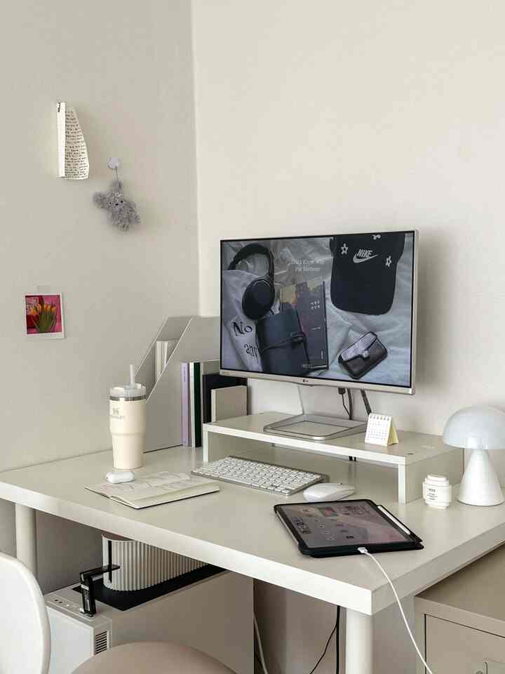 ホワイトトーンのホームオフィス、すっきりとしたデスクにモニター、ワイヤレスキーボード、タブレットが配置された落ち着いたミニマルな作業空間