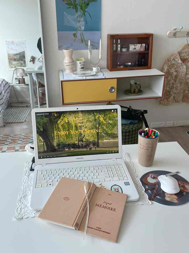 明るいホワイトとウッドトーンの調和したホームオフィス、デスク上にはノートパソコンと手帳、整頓された収納キャビネットが配置されたシンプルで集中できる空間