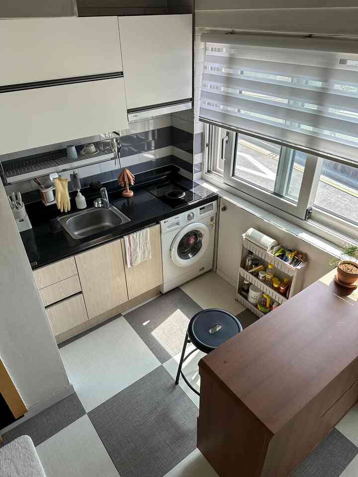 白と木目調のモダンなキッチン、スツールと大きな窓が配置された明るく清潔感のあるインテリア