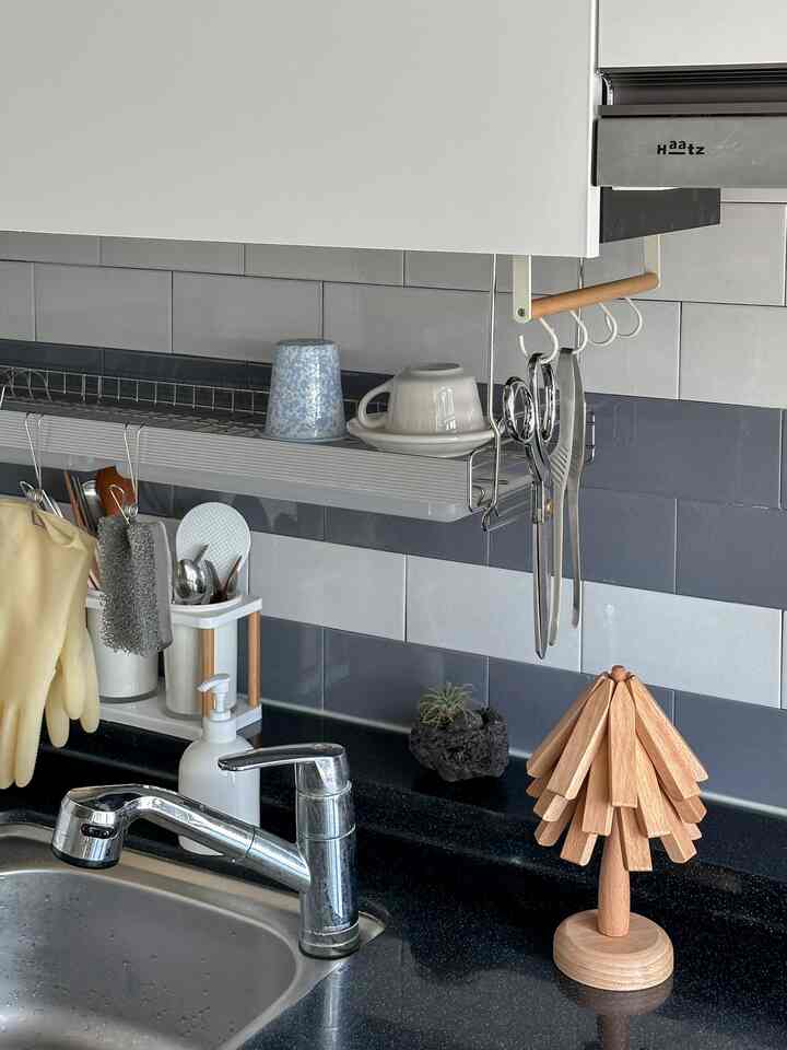 グレーと木目調のキッチン、木製の鍋敷きツリーとカトラリーが配置された印象的な空間