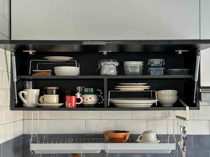 白と黒のトーンのキッチン上部収納、カップと皿が整頓された一人暮らしのホームカフェ空間