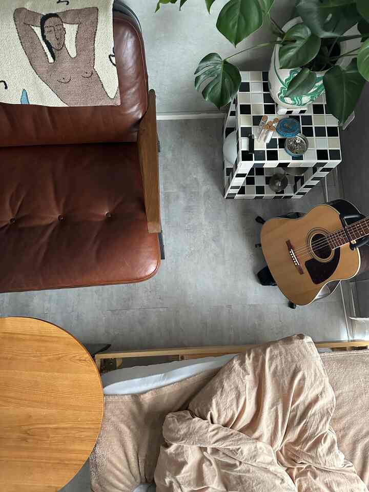 ブラウンレザーのソファと木目調のテーブルが配置されたグレーの床のリビング空間