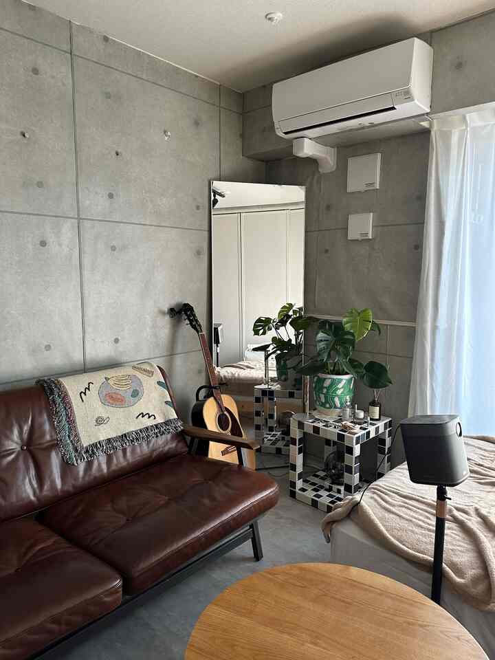 グレーのコンクリート壁とナチュラルトーンの家具が調和するカフェ風リビングスペース