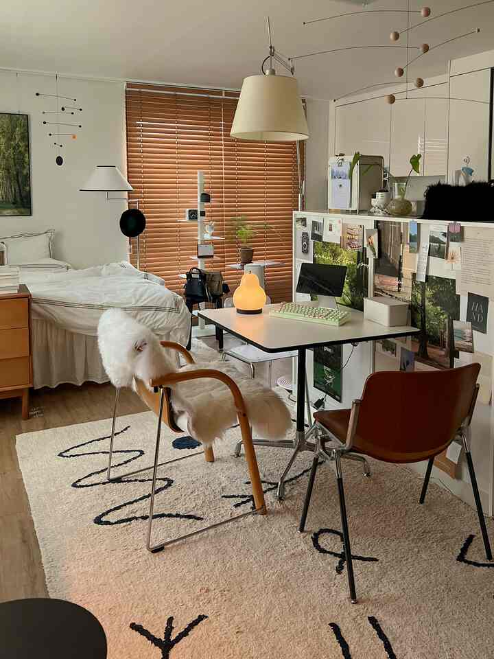 温かみのある木目調とナチュラルカラーが調和するワンルームの寝室兼ホームオフィス空間、ベッドと作業デスクが配置された居心地の良いインテリア