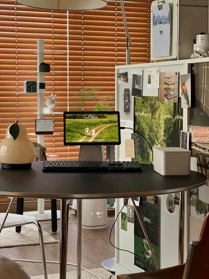 暖かみのある木目のブラインドと白いパーティションが配置されたモダンなワンルーム、机上にモニターとキーボードが整った清潔感のあるワークスペース