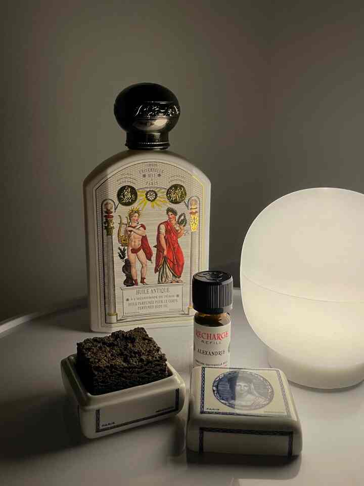 柔らかな白とベージュの色調の整った空間に香水瓶とオブジェが配置された雰囲気のあるインテリア