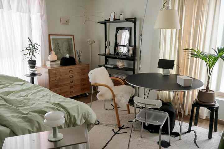 ホワイトとウッドトーンが調和した8坪のワンルーム寝室、丸テーブルやカーテン、植物が配置された清潔感のあるモダンな空間