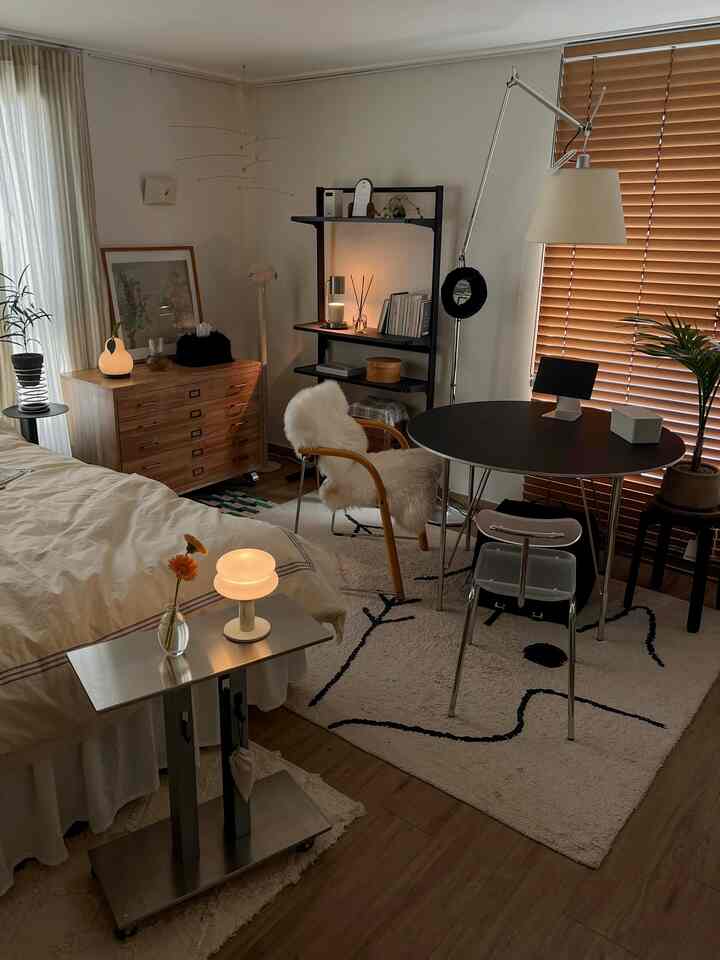 ウッドトーンとホワイトを基調としたワンルーム、ベッドと木製のドレッサー、ラグ、アクリルチェアや照明が配置された雰囲気のあるインテリア