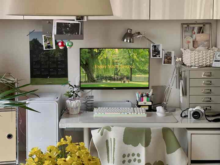 ホワイトとグリーンのトーンが調和したワンルームのホームオフィス、整頓されたデスクとパソコンモニターが配置された居心地の良い在宅勤務空間