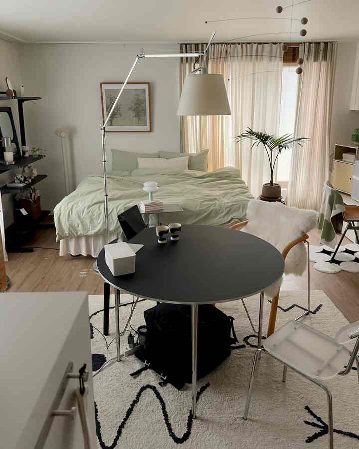 ホワイトとブラックトーンの8坪のワンルーム寝室、シンプルモダンスタイルのベッドと円形テーブル、アールデコ照明と植物が配置された雰囲気あるインテリア