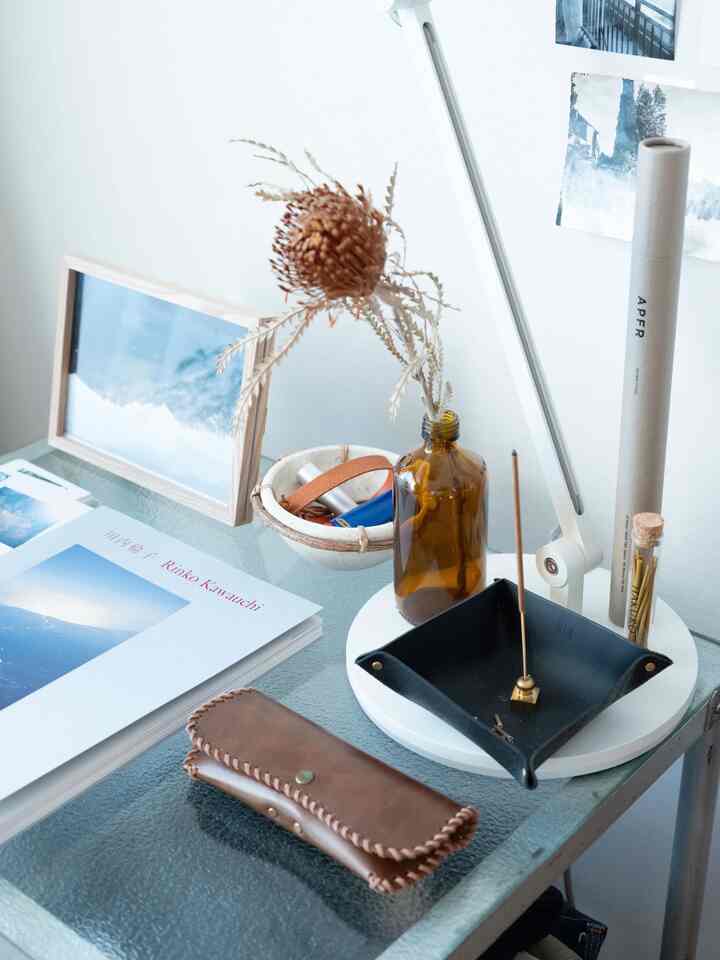 白、茶色、黒のトーンのコンパクトなワークスペース、ガラス製デスクと照明が配置されたモダンなインテリア