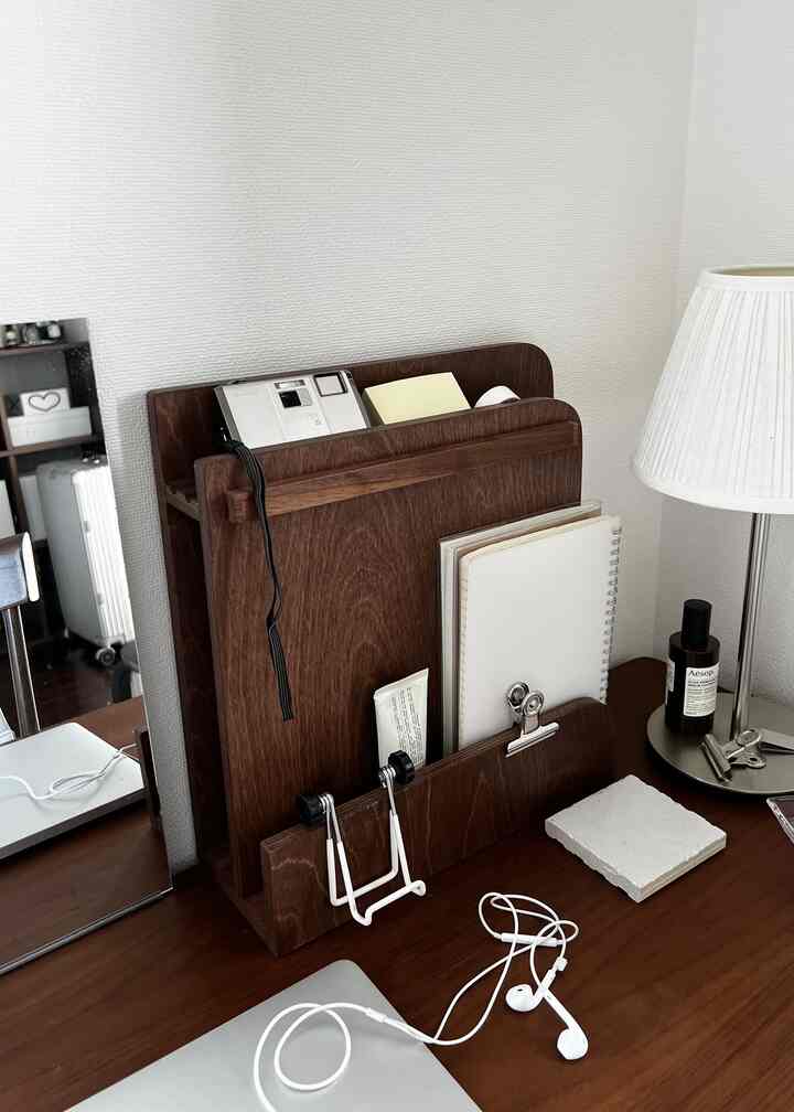 ダークブラウンの木目調で統一されたコンパクトなデスクスペース、整頓された机にオーガナイザーとテーブルランプが配置された雰囲気のあるインテリア