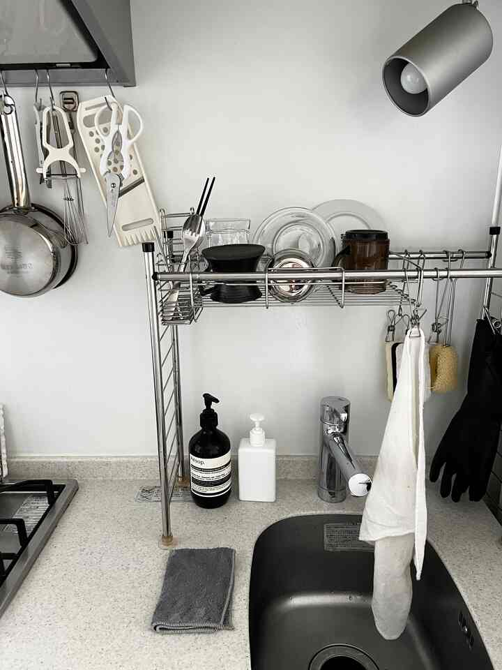 白とグレーのトーンのキッチン空間、ニトリの収納ラックと整頓されたタオルが配置された実用的なインテリア