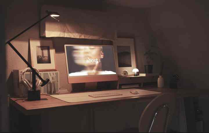 オレンジのiMacを中心に配置し、モノトーンの額縁と黒い照明が配された低い天井の落ち着いたホームオフィス空間