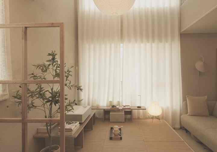 明るいベージュ色調のリビング、低い木製ダイニングテーブルと植物、ソファとカーテンが調和する自然なモダンなインテリア