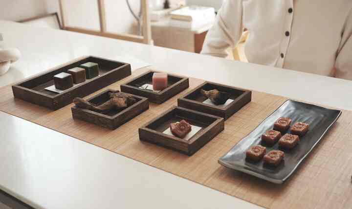 ナチュラルな色調のダイニングテーブルにアジアンスタイルの木製オブジェと伝統菓子が配置された雰囲気のあるインテリア