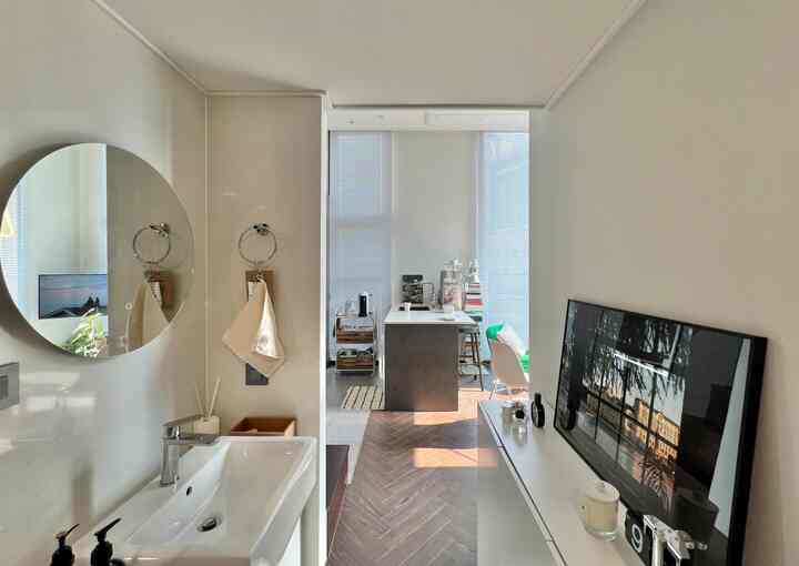 ホワイトと木目調が調和した狭い玄関、洗面台と広い収納が配置された清潔感のあるカフェ風インテリア