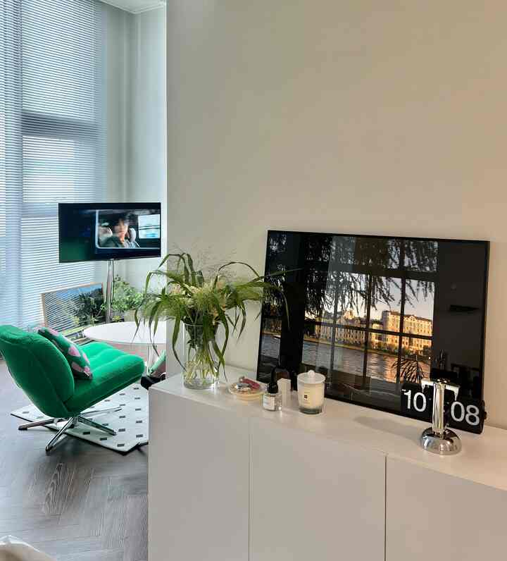 白と緑の調和が取れたモダンなリビング、丸いガラスの花瓶と緑のアームチェアが配置された落ち着いた雰囲気の空間