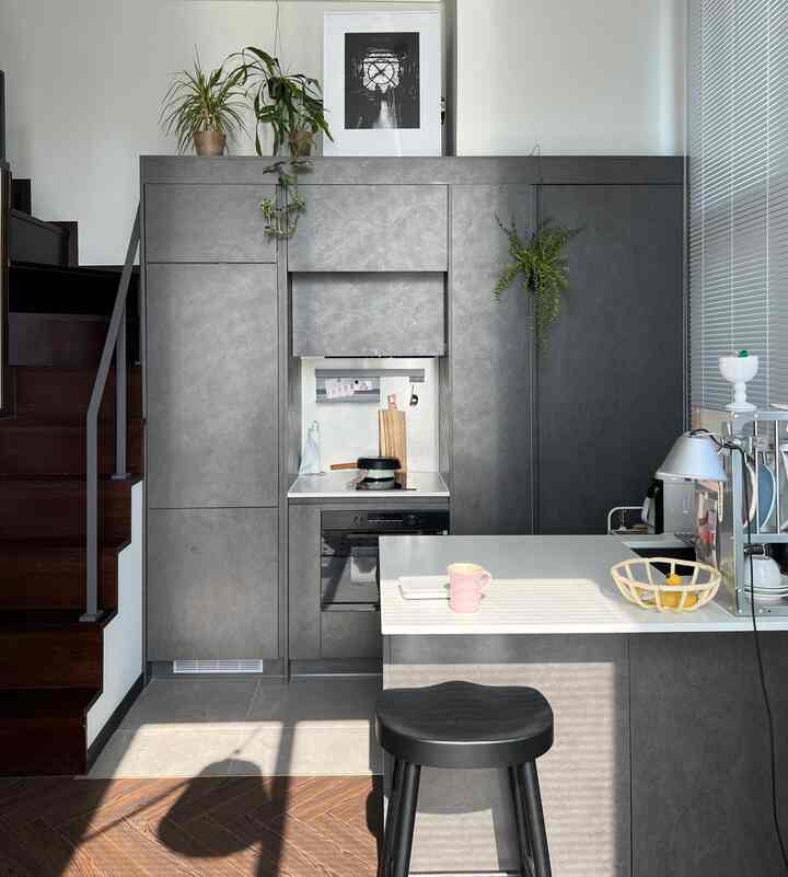 グレーと白のトーンのモダンなキッチン、上部に額縁と植物が配置された爽やかな雰囲気の空間